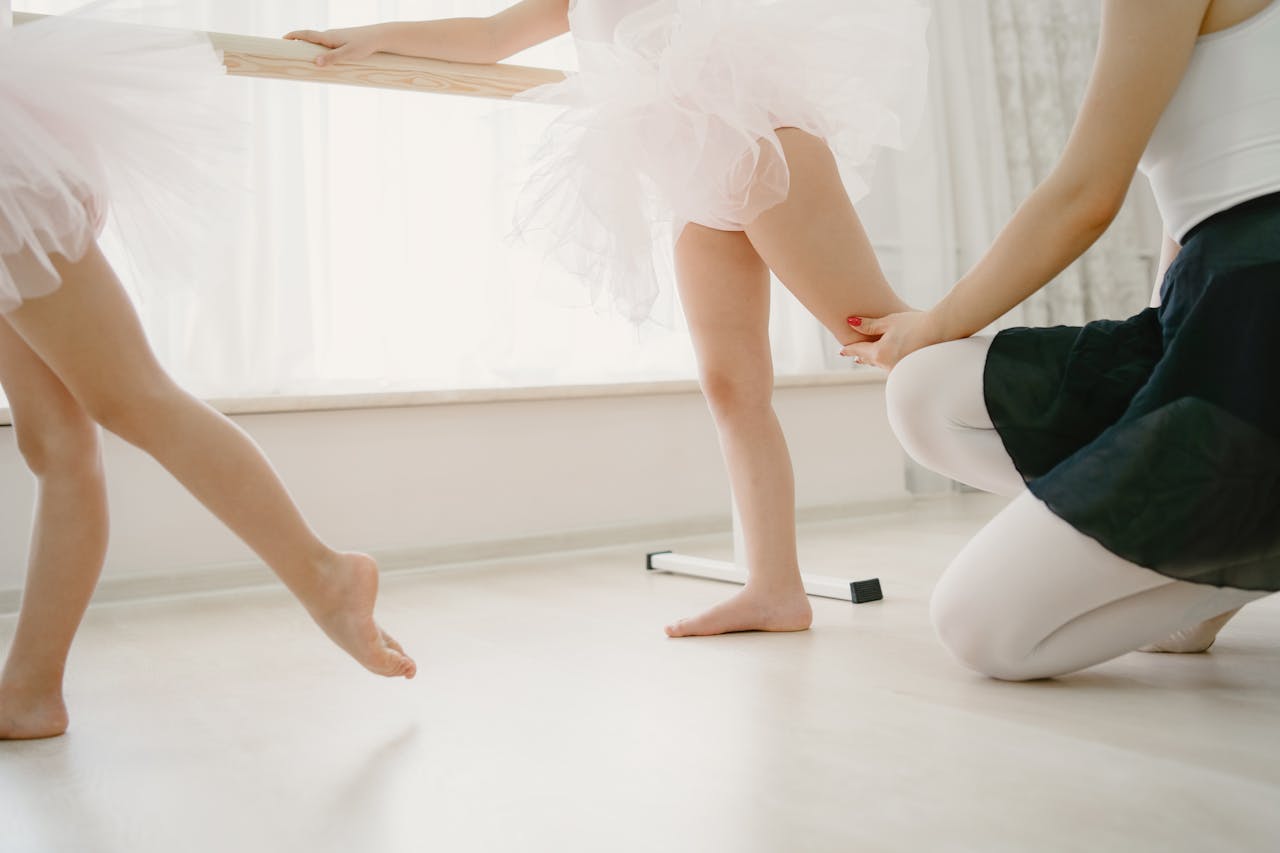 Children practicing ballet at barre with teachers guidance.