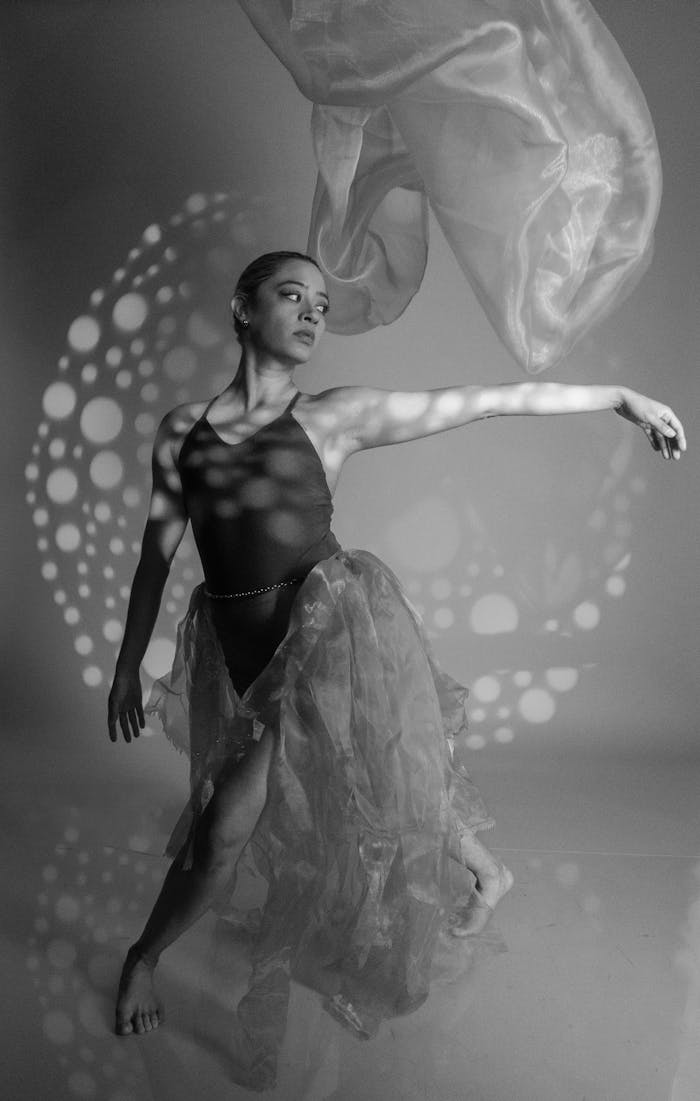 Black and white image of a female dancer performing with dynamic lighting and fabric motion.